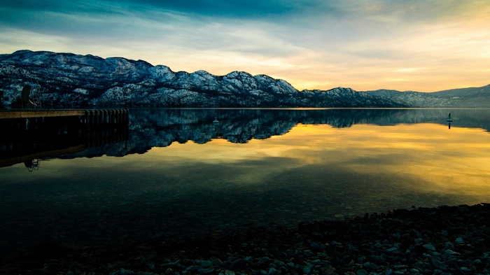 Snow-capped mountains reflected in a calm lake at sunset