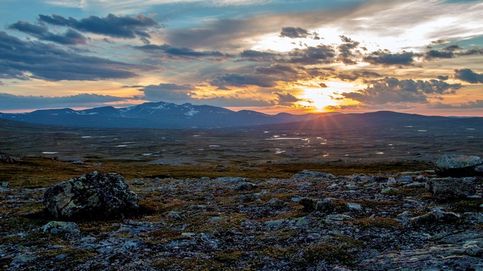 Sunset over a rocky, mountainous landscape with clouds