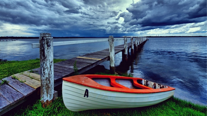 Boat by a wooden pier under stormy clouds