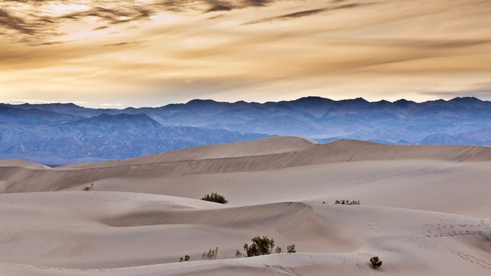 Sand dunes and mountains under a cloudy sky