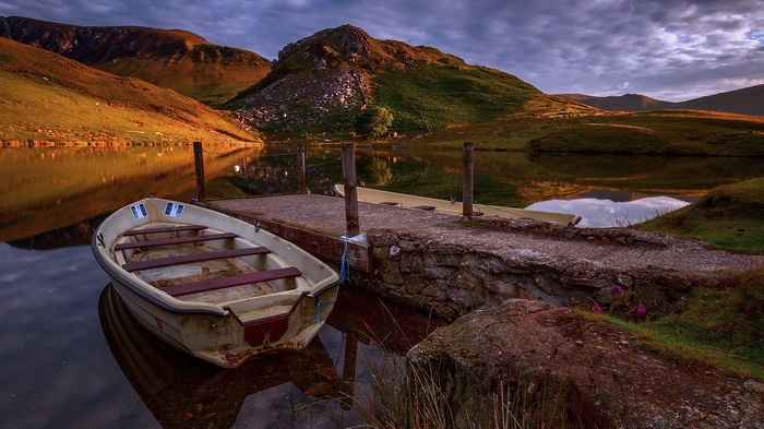 Rowboat docked on a lake with mountains at sunset