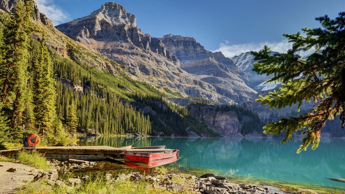 Red canoe on a wooden dock by a mountain lake