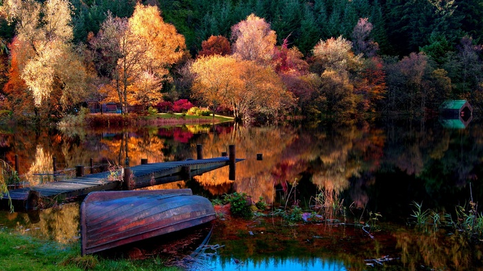 Autumn lake with wooden pier and overturned boat