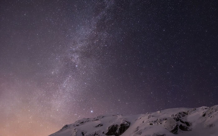 Starry night sky over snow-covered mountains