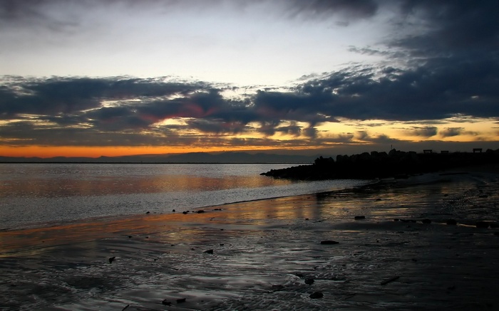 Sunset over a rocky beach with calm water