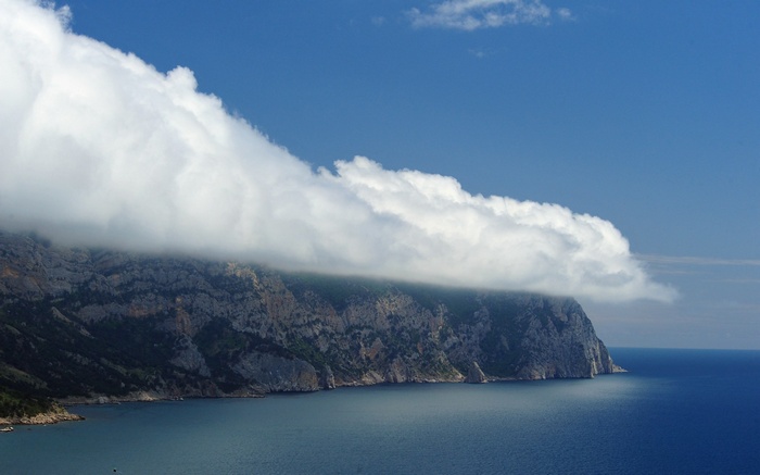 Clouds over a rocky coastline and blue sea