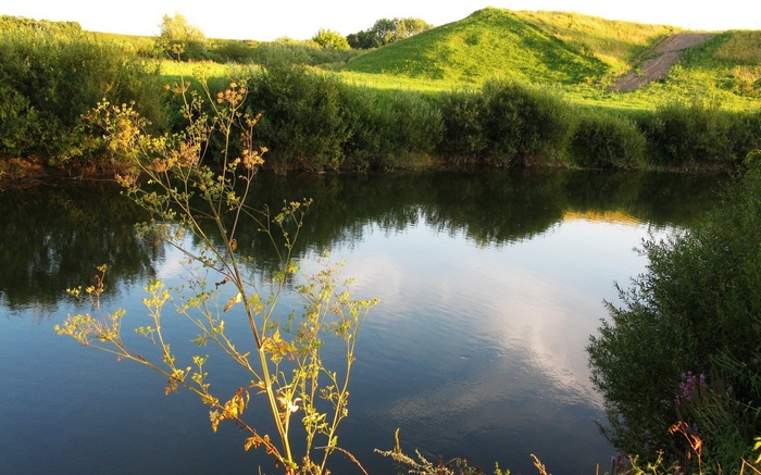 River reflecting green hills and trees