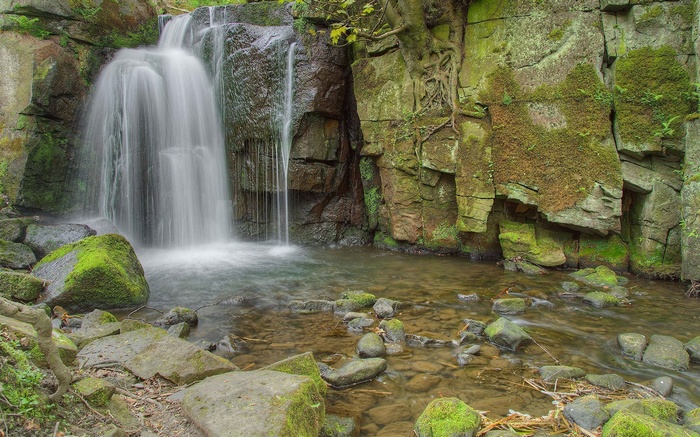 Waterfall cascading over mossy rocks into a shallow stream