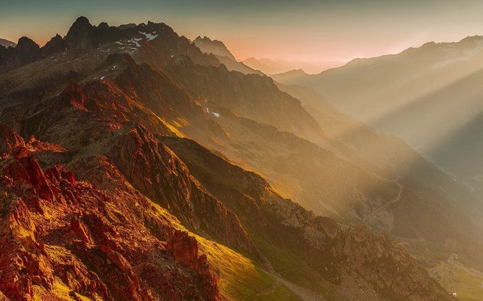 Sunlight streams through mountain peaks at sunset