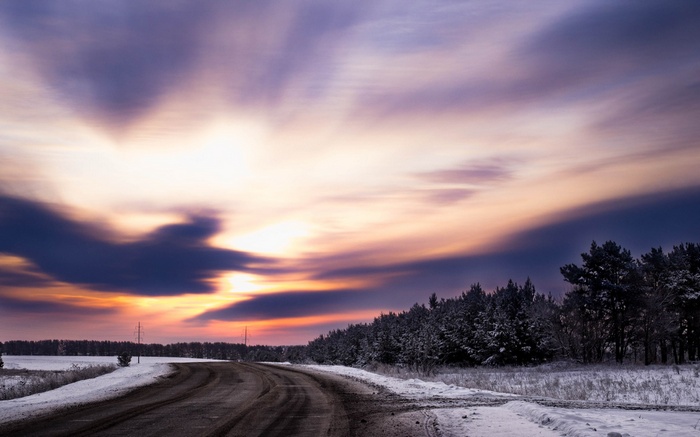Winding road through a snowy landscape at sunset