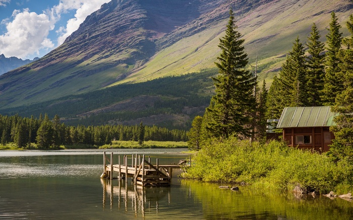 Wooden dock on a lake with a cabin and mountains