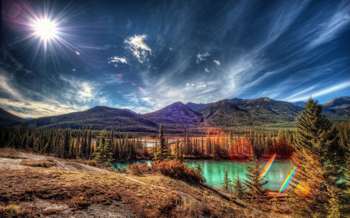 Sunlit mountain landscape with turquoise river and pine forest