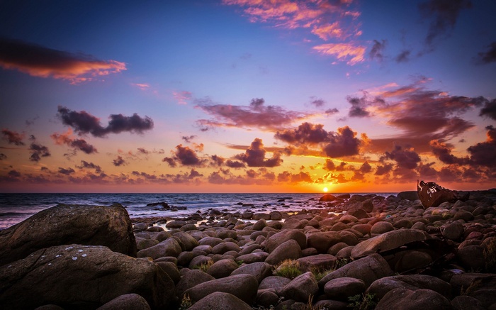 Sunset over rocky beach with shipwreck