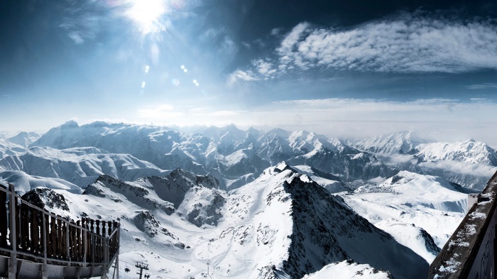Panoramic view of snow-covered mountains under a bright sun