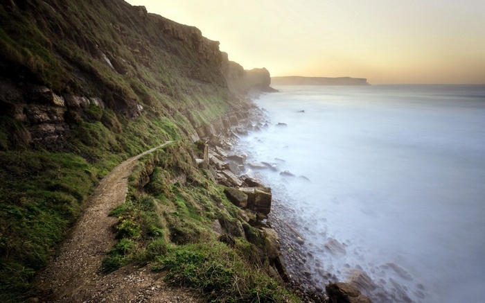 Coastal cliff path overlooking the sea at sunset