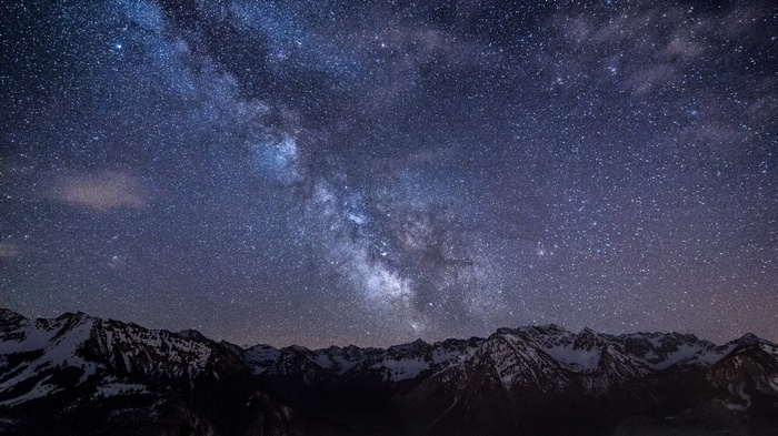Milky Way galaxy over snow-capped mountains at night