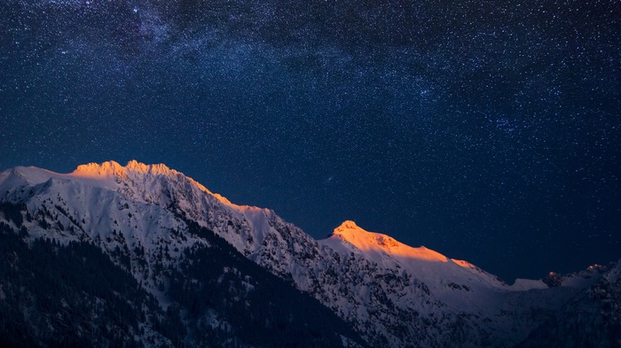 Snowy mountains under a starry night sky