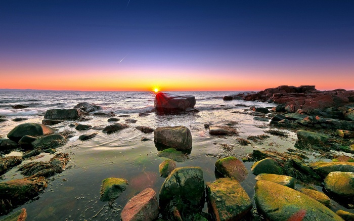 Sunset over rocky coastline with ocean waves