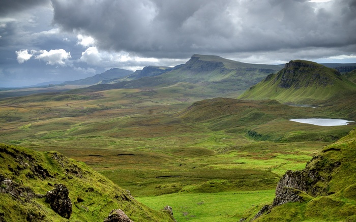 Rolling green hills and mountains under a cloudy sky