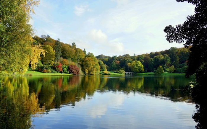 Autumn trees reflected in a lake with a bridge
