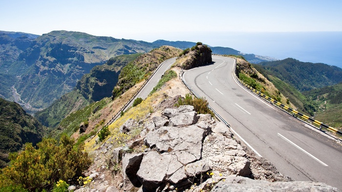 Mountain road winding along a steep cliff overlooking the ocean