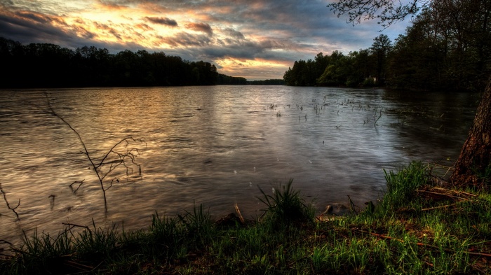 Lake at sunset with trees and clouds