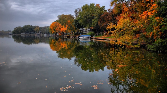 Autumn trees reflecting in a calm lake with a boat