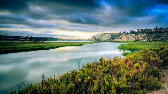 River flowing through a marsh with buildings on a hill