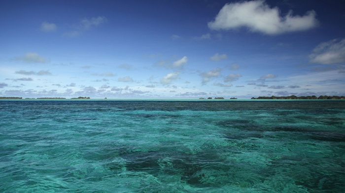 Turquoise ocean water with islands on the horizon under a blue sky