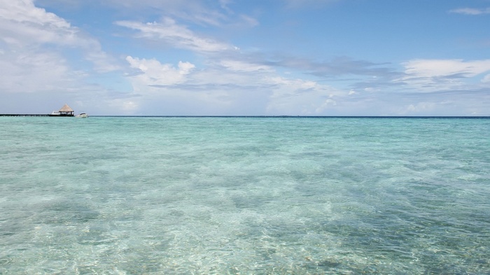 Calm turquoise ocean with a pier and hut