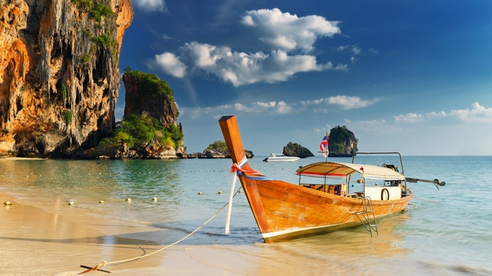 Longtail boat on a tropical beach with limestone cliffs