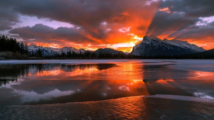 Sunset over snow-capped mountains and frozen lake in Alberta, Canada