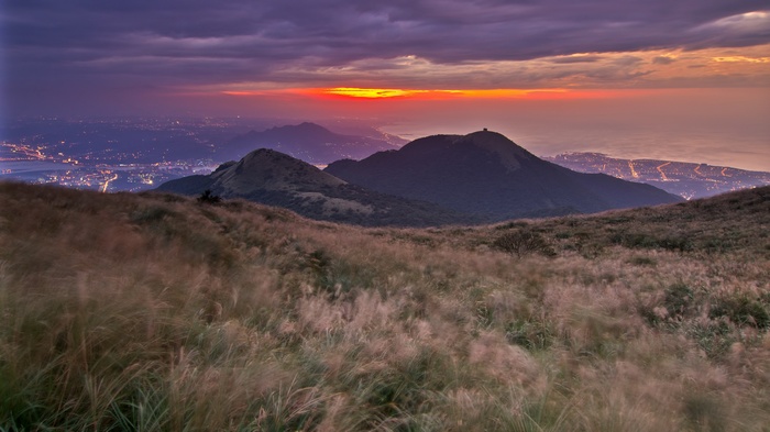 Mountain landscape with city lights at sunset