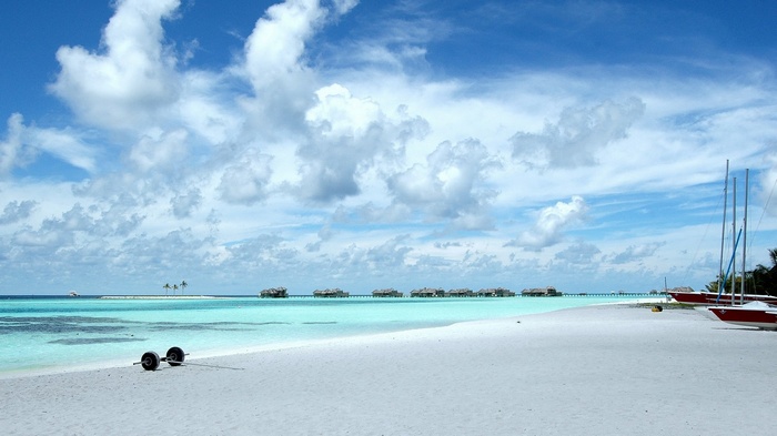 Overwater bungalows and sailboats on a tropical beach