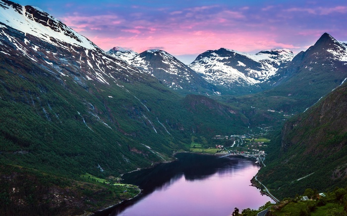 Snow-capped mountains overlooking a lake at sunset