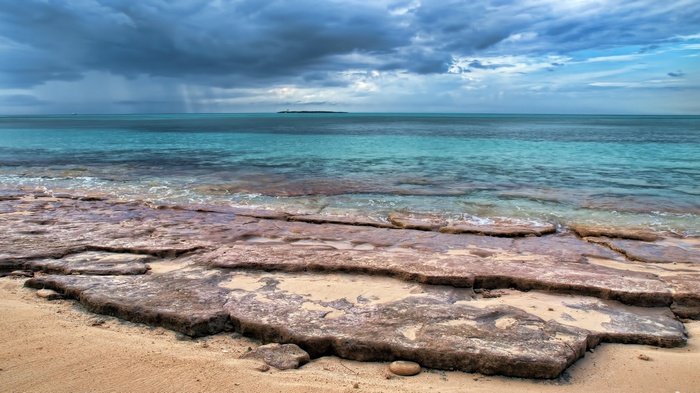 Rocky beach with turquoise water and stormy clouds