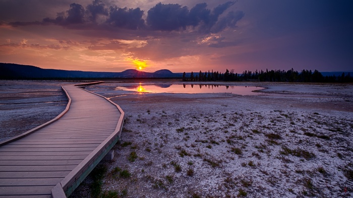 Boardwalk through a geothermal area at sunset