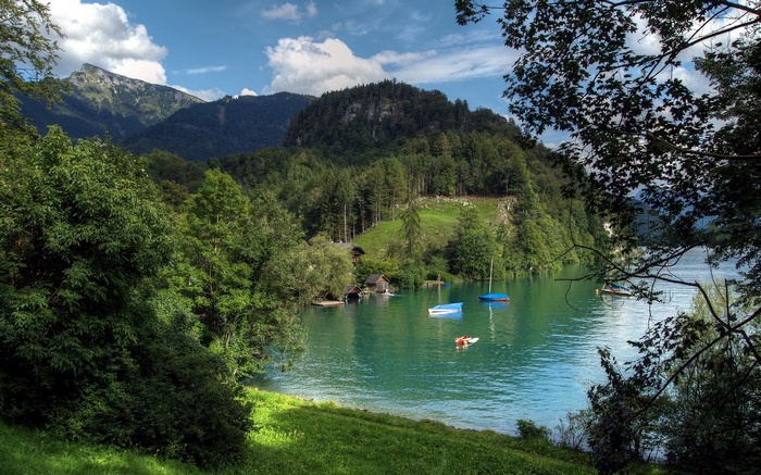 Boats on a turquoise lake with forested mountains