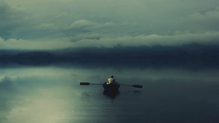 Man rowing a boat on a misty lake