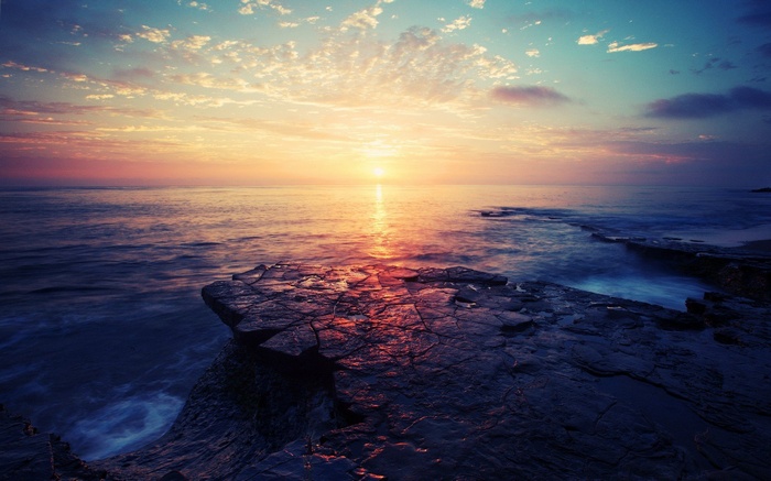 Sunset over the ocean with rocky shore