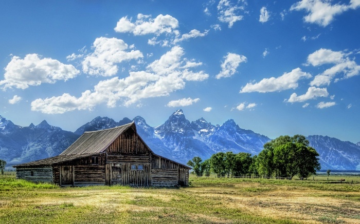 Wooden barn in front of mountains and trees
