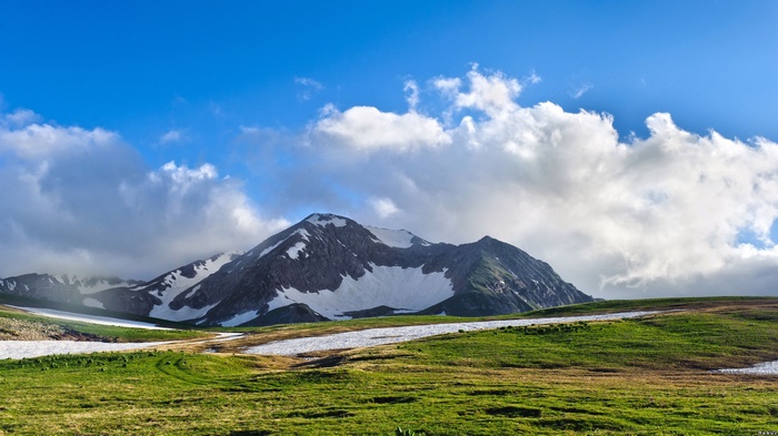 Snow-capped mountains under a blue sky with clouds