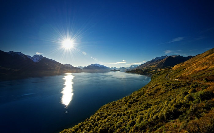 Sun over a lake and mountains