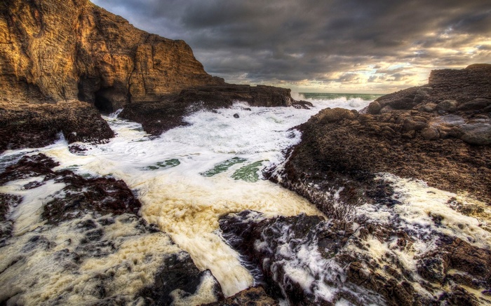 Waves crashing on rocky shore with sea foam