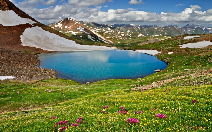 Alpine lake surrounded by mountains and wildflowers