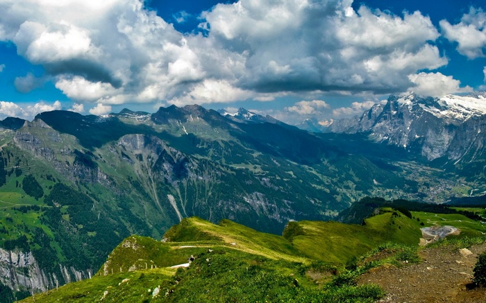 Panoramic view of Swiss Alps with green valleys and snow-capped peaks