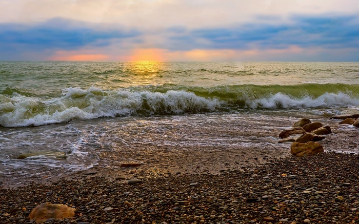 Waves crashing on a pebble beach at sunset
