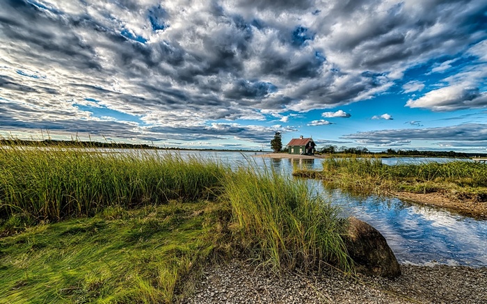 A small house on an island in a lake under a cloudy sky