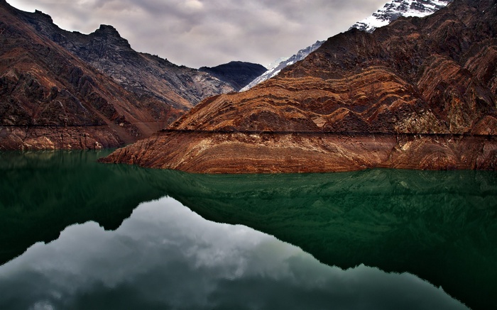 Mountain lake reflection under cloudy sky
