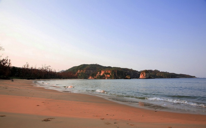 Beach with calm ocean and forested hills